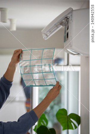 Woman removing dusty air conditioner coarse filter for washing, cleaning. Dust cause of illness Woman removing dusty air conditioner coarse filter for washing, cleaning. Dust cause of illness 140942558