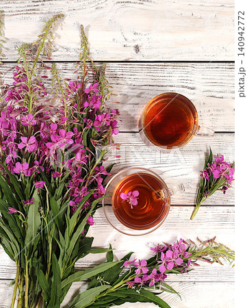 Medicinal herbal tea or fireweed infusion in a glass with flowers, alternative folk medicine concept, green pharmacy advertisement, collection of useful herbs for treatment according to folk recipes Medicinal herbal tea or fireweed infusion in a glass with flowers, alternative folk medicine concept, green pharmacy advertisement, collection of useful herbs for treatment according to folk recipes 140942772