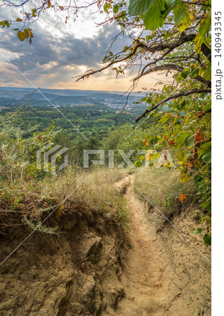 Curve road to the mountains. Scenic dirt road with mountain range. 140943345
