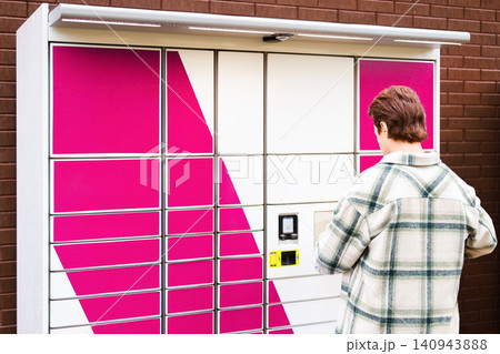 Man at a self-service terminal of a parcel locker for an easy pickup. Enjoying convenient ecommerce shopping with secure contactless delivery technology and logistics service. Man at a self-service terminal of a parcel locker for an easy pickup. Enjoying convenient ecommerce shopping with secure contactless delivery technology and logistics service. 140943888