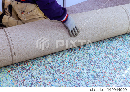 Contractor is laying down carpet on floor of room preparation for installation work. Contractor is laying down carpet on floor of room preparation for installation work. 140944099
