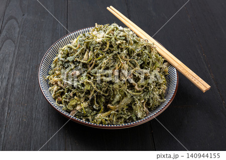 Traditional Chinese steamed flour coated dandelion greens on porcelain plate with chopsticks Traditional Chinese steamed flour coated dandelion greens on porcelain plate with chopsticks 140944155