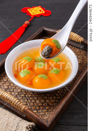 cooked persimmon shaped sweet rice ball with flowing black sesame filling, authentic festive Chinese Tangyuan dessert cooked persimmon shaped sweet rice ball with flowing black sesame filling, authentic festive Chinese Tangyuan dessert 140944673