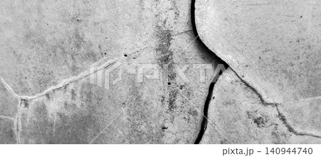 A cracked concrete wall texture featuring deep fissures, weathered plaster layers, and a rough, granular surface. A cracked concrete wall texture featuring deep fissures, weathered plaster layers, and a rough, granular surface. 140944740