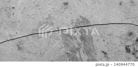 The gray concrete wall surface reveals long horizontal cracks and a natural cement texture that appears weathered. The gray concrete wall surface reveals long horizontal cracks and a natural cement texture that appears weathered. 140944770