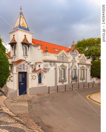 Historic Portuguese house decorated with blue azulejo tiles and a traditional red tiled roof on a quiet street in Cascais, Portugal. 140944806