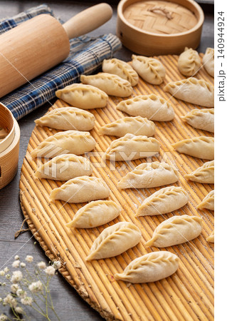 raw handmade Chinese steamed dumplings, unbaked leaf shaped Jiaozi with flour dust, traditional food preparation raw handmade Chinese steamed dumplings, unbaked leaf shaped Jiaozi with flour dust, traditional food preparation 140944924