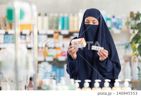 Young woman in hijab chooses pills 140945553