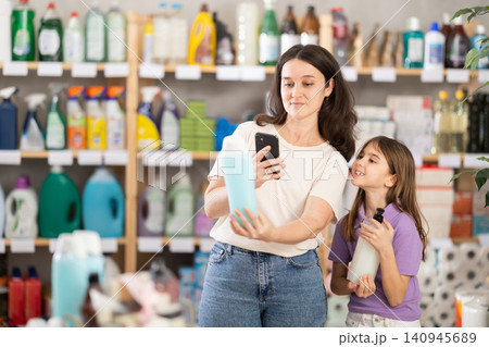 Woman and girl clients, by scanning QR code, gain access to information about shampoo 140945689