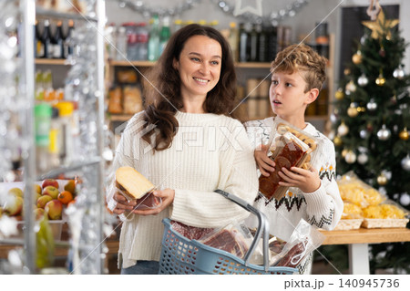 Adolescence boy with mother choose consider snacks in shop on eve of New Year 140945736
