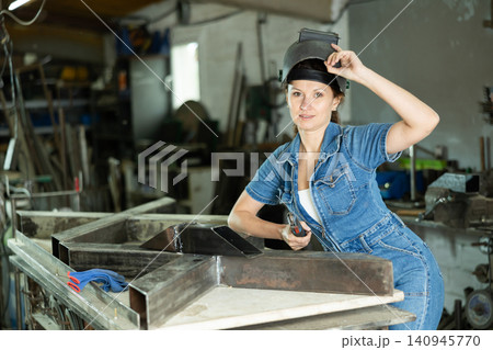 During manufacture of product, woman employee works with welding machine During manufacture of product, woman employee works with welding machine 140945770