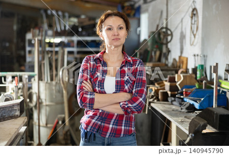 Female employee of workshop stands next to vise, resting from labors Female employee of workshop stands next to vise, resting from labors 140945790
