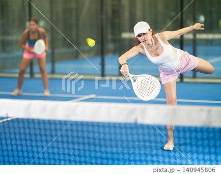 Young and adult women playing doubles tennis Young and adult women playing doubles tennis 140945806