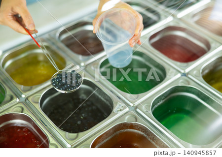 Hands of barista preparing adding black bubble tea pearls into cup Hands of barista preparing adding black bubble tea pearls into cup 140945857