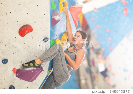 Woman in sportswear practicing rock climbing on climbing wall 140945877
