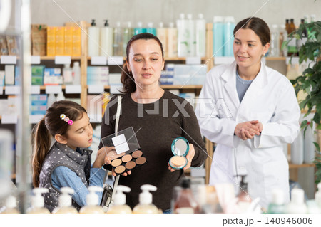 Middle-aged woman with daughter choosing cosmetics in drugstore 140946006