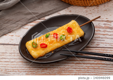 fried rice cake skewers seasoned with sliced red and green chili peppers. 140946099