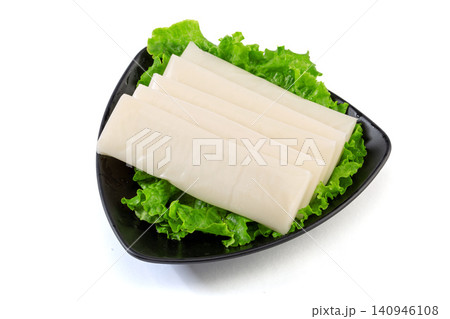 Raw white rice cake slices arranged with fresh green lettuce leaves. Raw white rice cake slices arranged with fresh green lettuce leaves. 140946108
