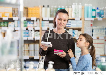 Woman with daughter choosing paracetamol in pharmacy Woman with daughter choosing paracetamol in pharmacy 140946189