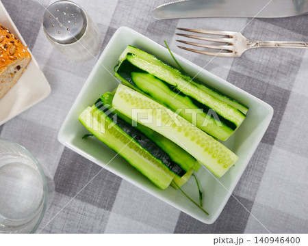 On table there is plate with summer snack - long pieces of cucumber pulp On table there is plate with summer snack - long pieces of cucumber pulp 140946400