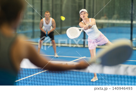 Adult woman and young man playing tennis against woman Adult woman and young man playing tennis against woman 140946493