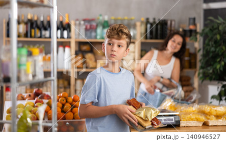 Joyful teenage boy choosing and buying different candies and sweets in supermarket Joyful teenage boy choosing and buying different candies and sweets in supermarket 140946527