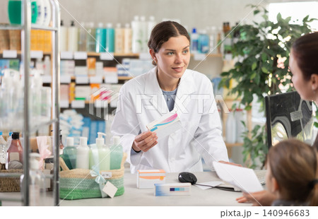 Pharmacist helping woman with girl choose medications at pharmacy Pharmacist helping woman with girl choose medications at pharmacy 140946683