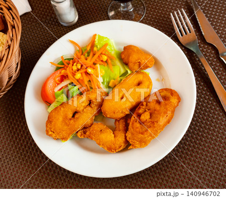 Fried coated squid rings with fresh vegetable salad 140946702