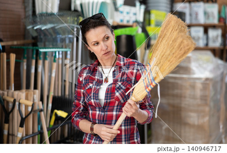 Woman shopping at hardware store - choosing broom Woman shopping at hardware store - choosing broom 140946717