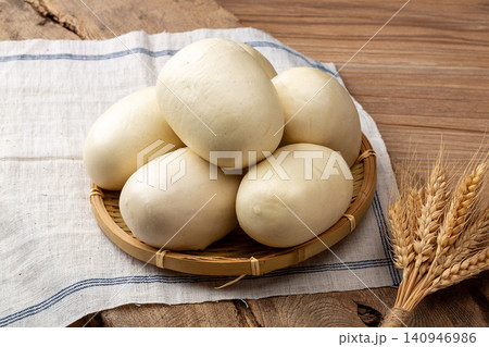 pair of fluffy white Chinese steamed buns in a traditional woven rattan basket 140946986