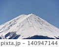 青空の下でベッタリ冠雪して白く化粧した富士山頂と森林限界以下の木々に着雪して鼠色になった樹林の裾野 140947144