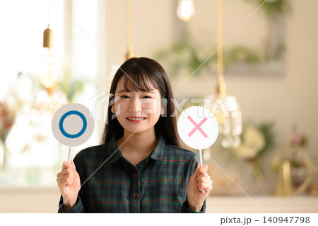 丸とバツの札を掲げる若い女性 140947798