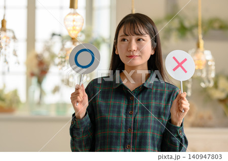 丸とバツの札を持つ若い女性 丸とバツの札を持つ若い女性 140947803