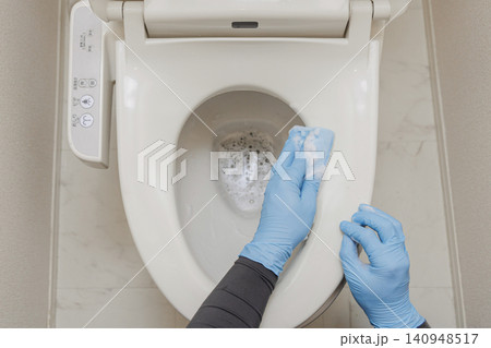 青い手袋の手が泡立つスポンジで温水洗浄便座を掃除するトイレ清掃の俯瞰ショット 青い手袋の手が泡立つスポンジで温水洗浄便座を掃除するトイレ清掃の俯瞰ショット 140948517