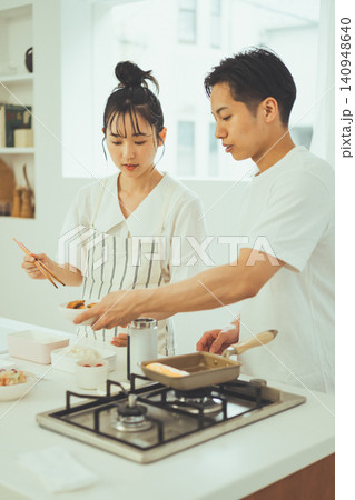 真剣な表情でお弁当の調理作業をするカップル 真剣な表情でお弁当の調理作業をするカップル 140948640
