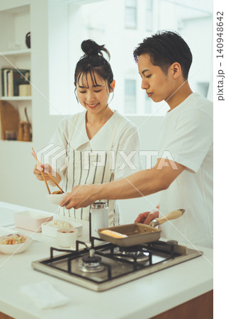 ガスコンロの前でお弁当の準備をする笑顔のカップル ガスコンロの前でお弁当の準備をする笑顔のカップル 140948642