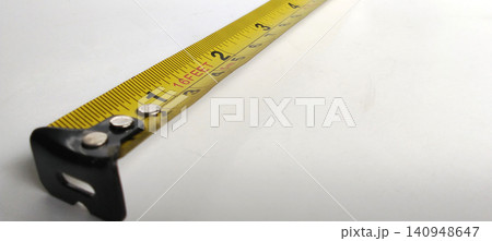 A close-up photo of a yellow measuring tape extended across a white surface. A close-up photo of a yellow measuring tape extended across a white surface. 140948647