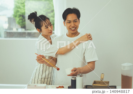 キッチンで料理中に男性に寄り添う笑顔のカップル キッチンで料理中に男性に寄り添う笑顔のカップル 140948817