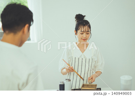 玉子焼きを焼く女性を見守る男性とキッチンの風景 玉子焼きを焼く女性を見守る男性とキッチンの風景 140949003