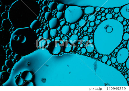 Macro scene shows turquoise bubbles, foam cells, and glossy droplets suspended in dark fluid, creating vivid organic texture for science or design backgrounds 140949239