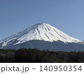 広い青空の下で三峰型山頂で長辺三角形の安定した形でどっしりとそびえたつ純白に冠雪した富士山 140950354