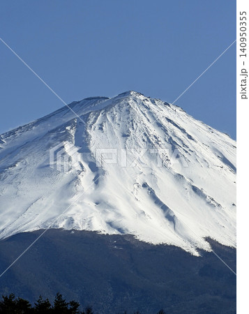 青空の下で三峰型山頂で安定した形でどっしりとそびえたつ純白に冠雪した富士山 140950355