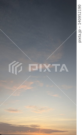 A beautiful vertical dawn landscape view captures soft pink tinted clouds drifting across a peaceful pale blue pastel sky during a calm sunrise. The gentle gradient color transition creates a serene A beautiful vertical dawn landscape view captures soft pink tinted clouds drifting across a peaceful pale blue pastel sky during a calm sunrise. The gentle gradient color transition creates a serene 140952190