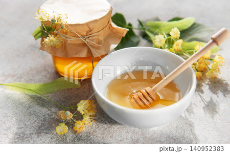 Fresh linden honey jar and bowl with dipper Fresh linden honey jar and bowl with dipper 140952383