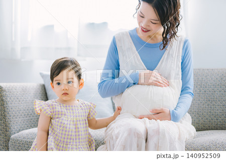 リビングで遊ぶ女の子と妊婦のお母さん リビングで遊ぶ女の子と妊婦のお母さん 140952509