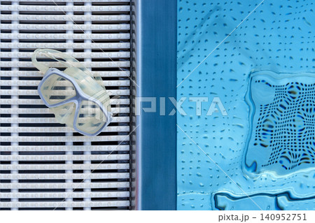 swimming goggles resting on a bench at the poolside in a relaxed top-down view with blue and white colors swimming goggles resting on a bench at the poolside in a relaxed top-down view with blue and white colors 140952751