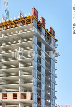 Construction of a tall building in an urban area with cranes and scaffolding 140953062