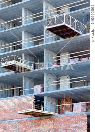Construction activity at a building site with scaffolding and brickwork taking place in an urban area during daylight hours Construction activity at a building site with scaffolding and brickwork taking place in an urban area during daylight hours 140953063