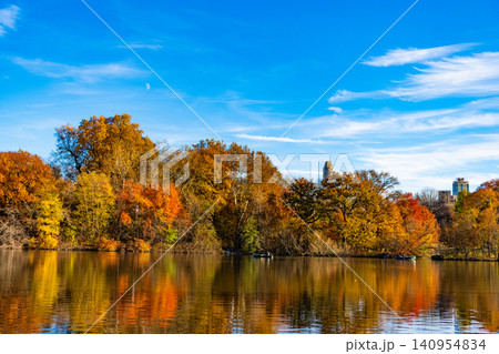 Autumn landscape. Fall nature. Rowboat on a small lake at the Central Park. Central Park Lake in autumn with people rowing boat. Central Park on sunny autumn day change colors. Lake serenity Autumn landscape. Fall nature. Rowboat on a small lake at the Central Park. Central Park Lake in autumn with people rowing boat. Central Park on sunny autumn day change colors. Lake serenity 140954834