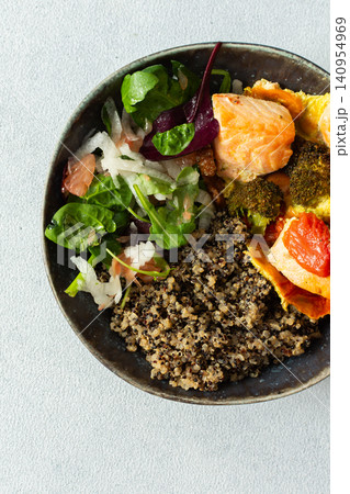 A quinoa bowl is filled with baked salmon, broccoli, tomatoes, and a fresh salad. This dish is good for breakfast or lunch and is rich in protein and nutrients A quinoa bowl is filled with baked salmon, broccoli, tomatoes, and a fresh salad. This dish is good for breakfast or lunch and is rich in protein and nutrients 140954969